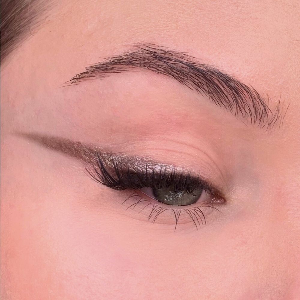 Auge mit Eyeliner. Das obere Augenlid hat einen Eyeliner-Strich. Wimpern und Augenbrauen sind sichtbar.