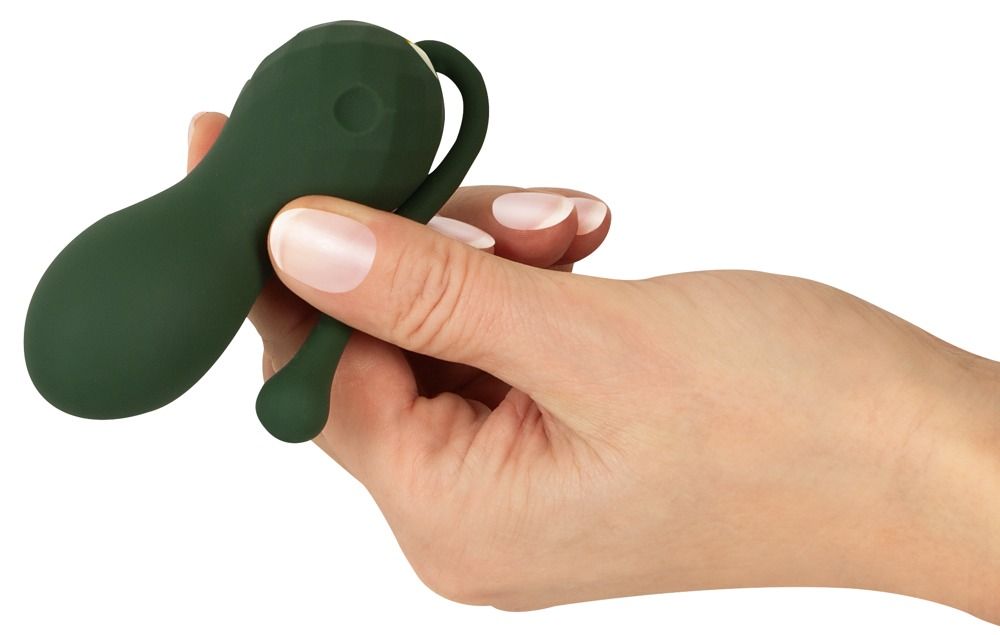 Grüne RC Love Balls in einer Hand gehalten. Die Kugeln haben eine facettierte Oberfläche und einen Ring. Der Hintergrund ist weiß.