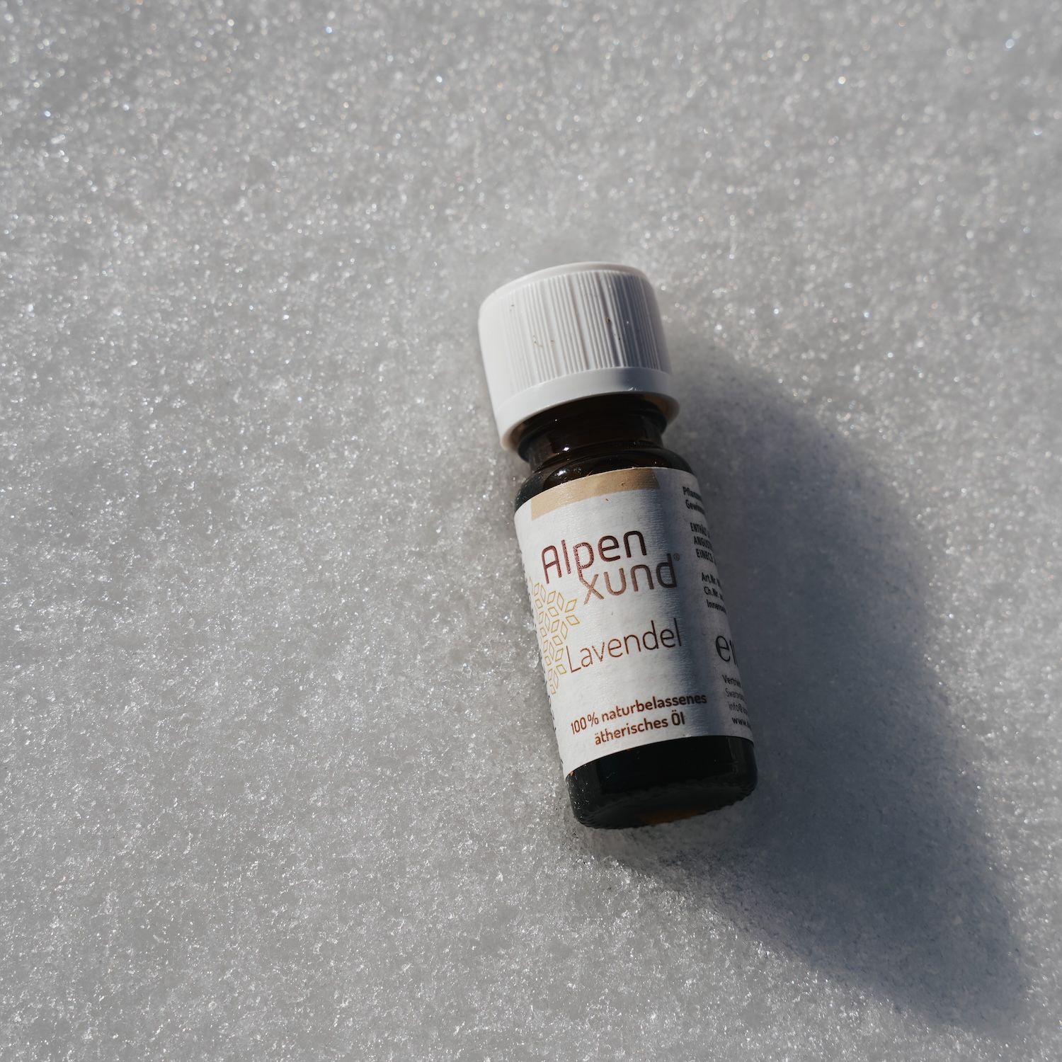 Braune Glasflasche mit weißem Deckel. Etikett mit AlpenXund und Lavendel. Auf weißem Untergrund.
