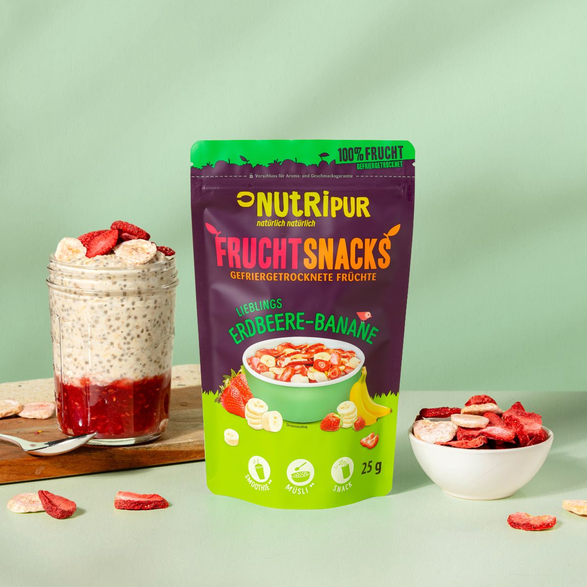 Produktverpackung und ein Glas mit Chia-Pudding und gefriergetrockneten Erdbeeren und Bananen. Schale mit Früchten.