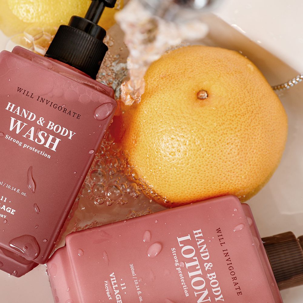 Zwei rosa Lotion-Flaschen mit Pumpköpfen. Aufschrift: Hand & Body Wash und Hand & Body Lotion. Marke: Village 11 Factory. Daneben eine Grapefruit.