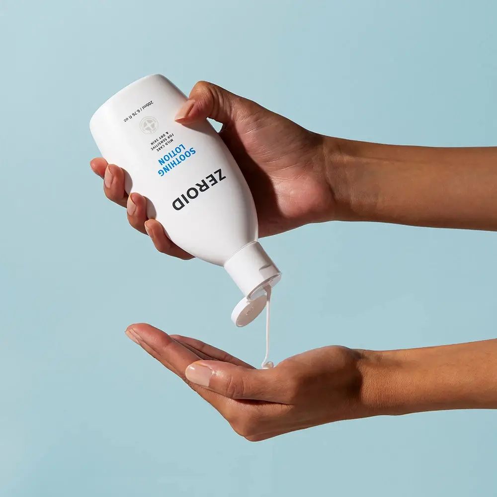 Hände halten ZEROID-Flasche. Lotion wird in die Handfläche gegossen. Blauer Hintergrund.