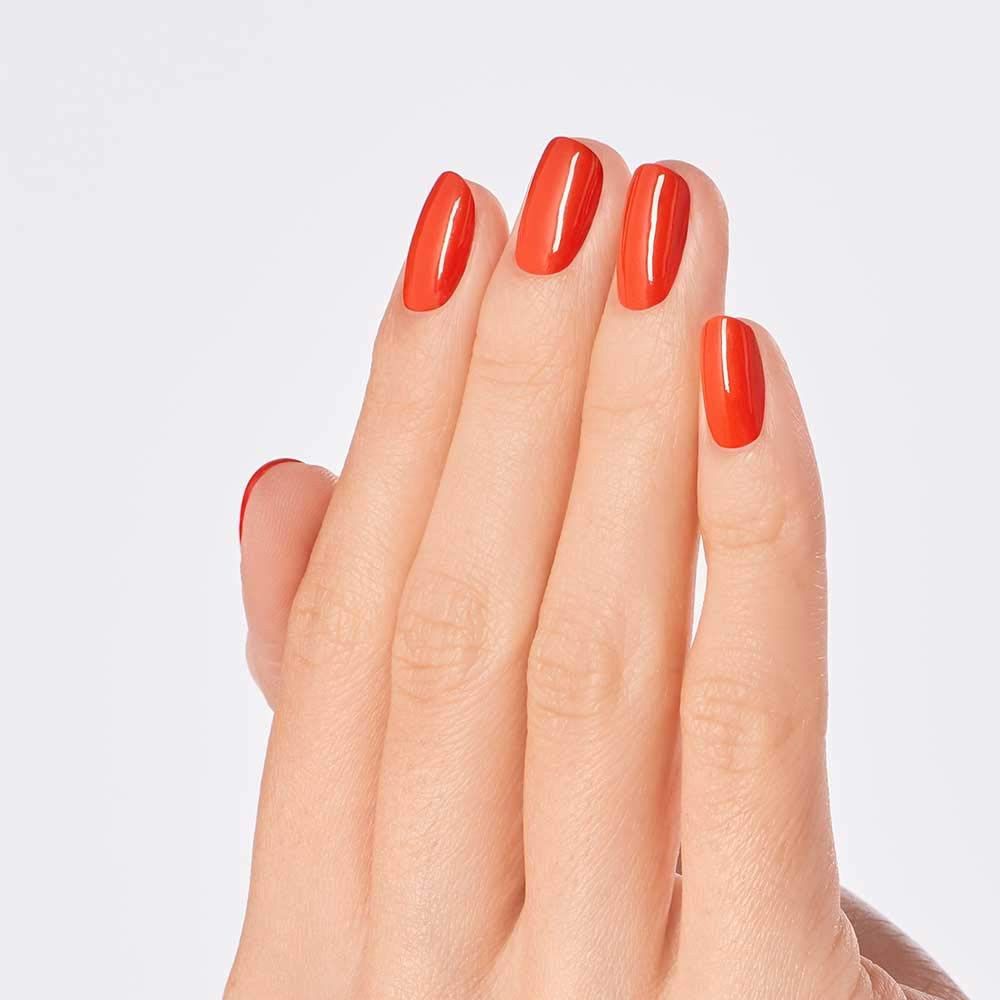 Hand mit lackierten Nägeln in Orange. Auf hellem Hintergrund.