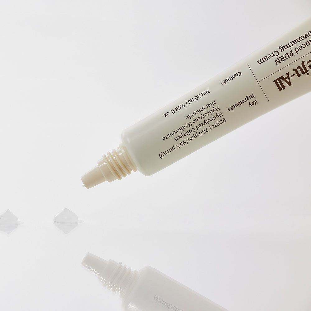 Eine Tube Dr. Reju-All Advanced PDRN Rejuvenating Cream, aus der drei kleine Tropfen Creme austreten.
