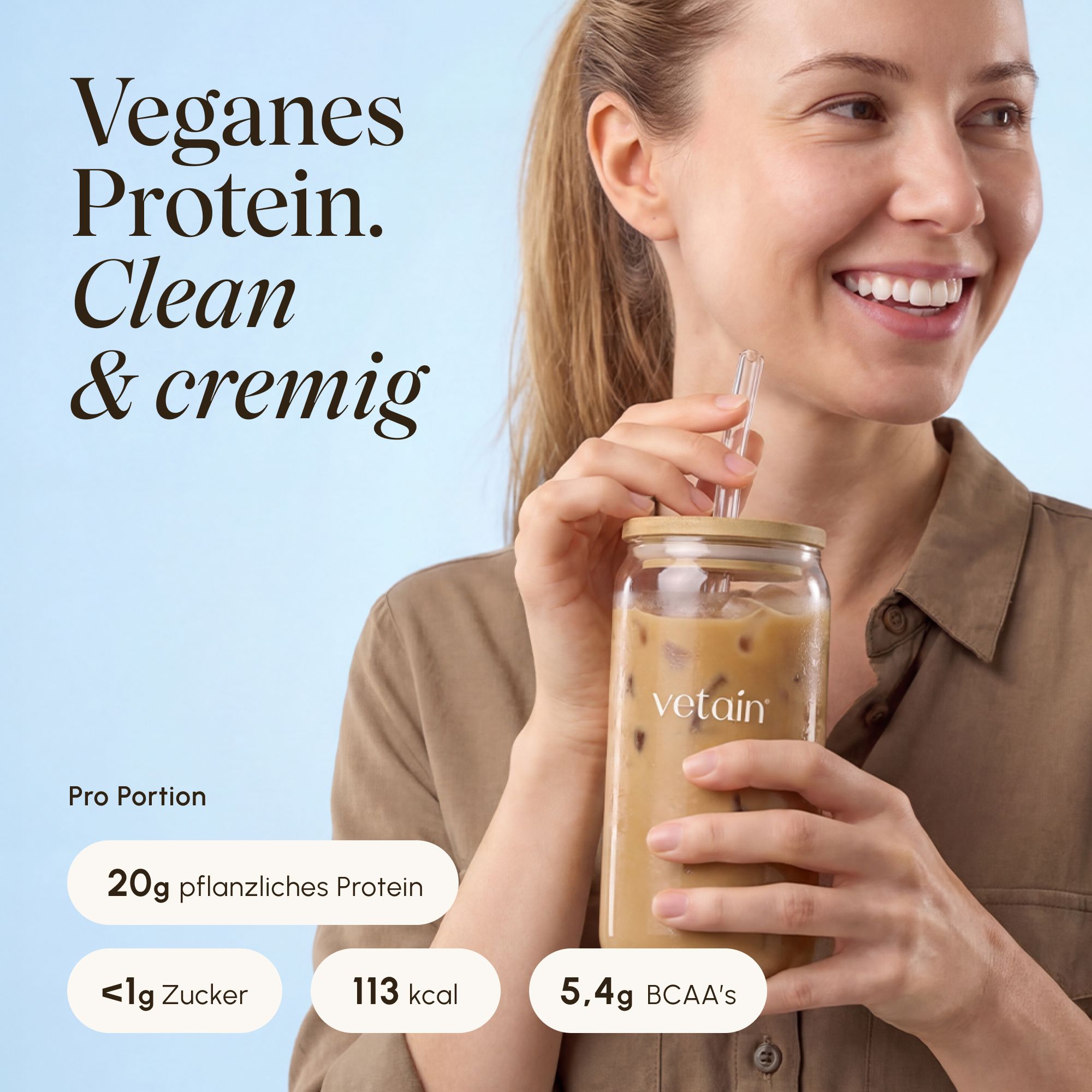 Frau genießt einen cremigen VETAIN Vegan Protein Iced Coffee aus einem Glas.