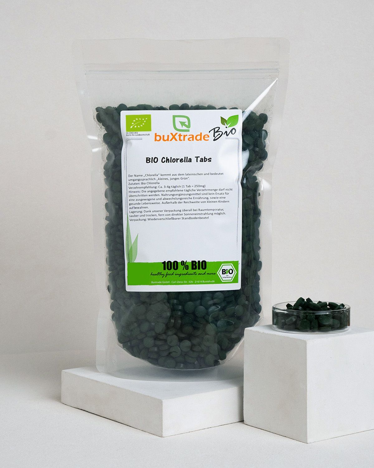 Ein Beutel buxtrade Bio Chlorella Tabs neben einer kleinen Schale mit Tabletten.