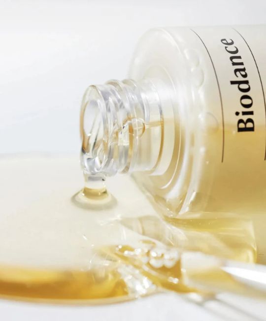 BIODANCE Skin Glow Vital Ampoule Serum tropft aus einem Glasfläschchen. Klare, gelbe Flüssigkeit.