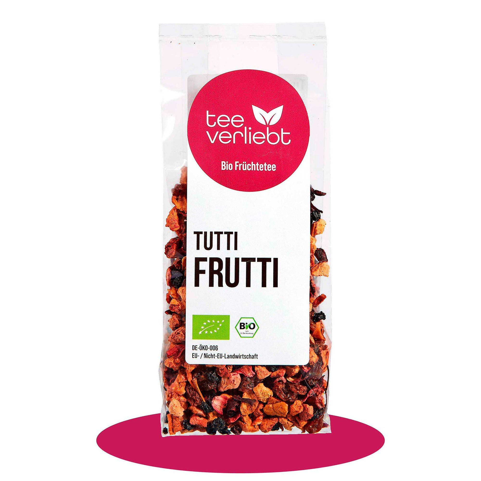 Transparente Verpackung mit losem Früchtetee. Runder Aufkleber mit Logo und Schriftzug 'tee verliebt'. Text 'TUTTI FRUTTI' und Bio-Siegel.