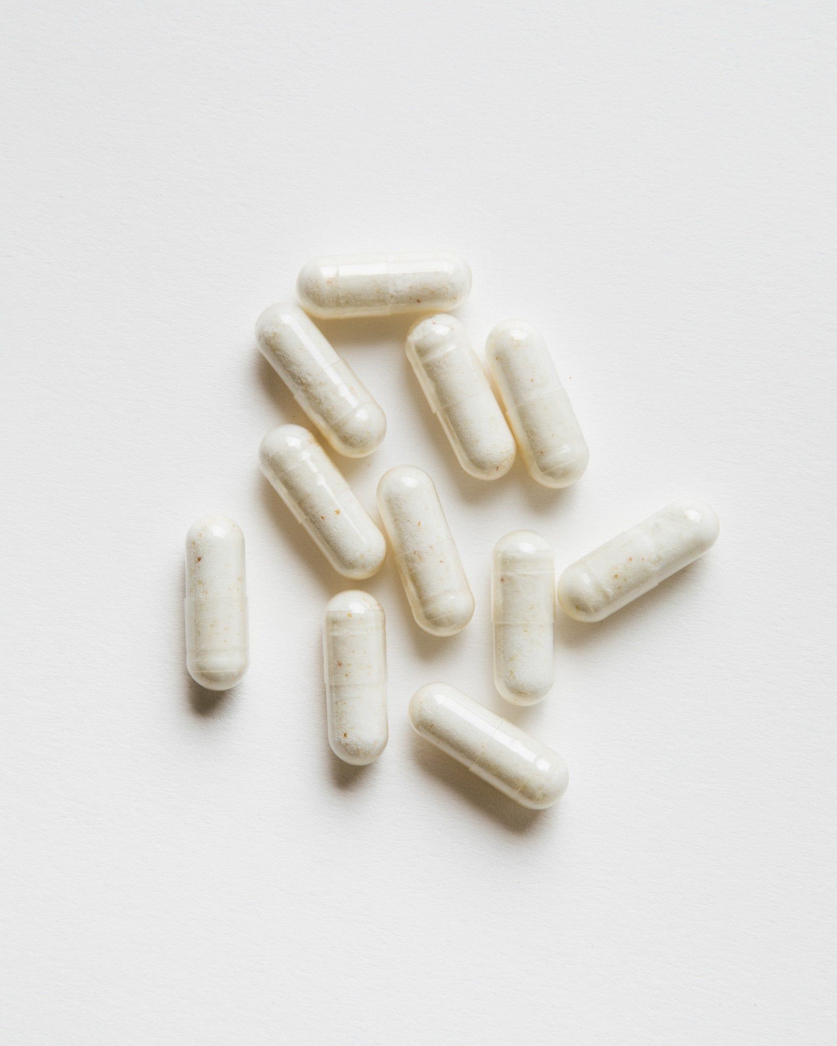 Kapseln auf weißem Hintergrund. Mehrere ovale, helle Kapseln.