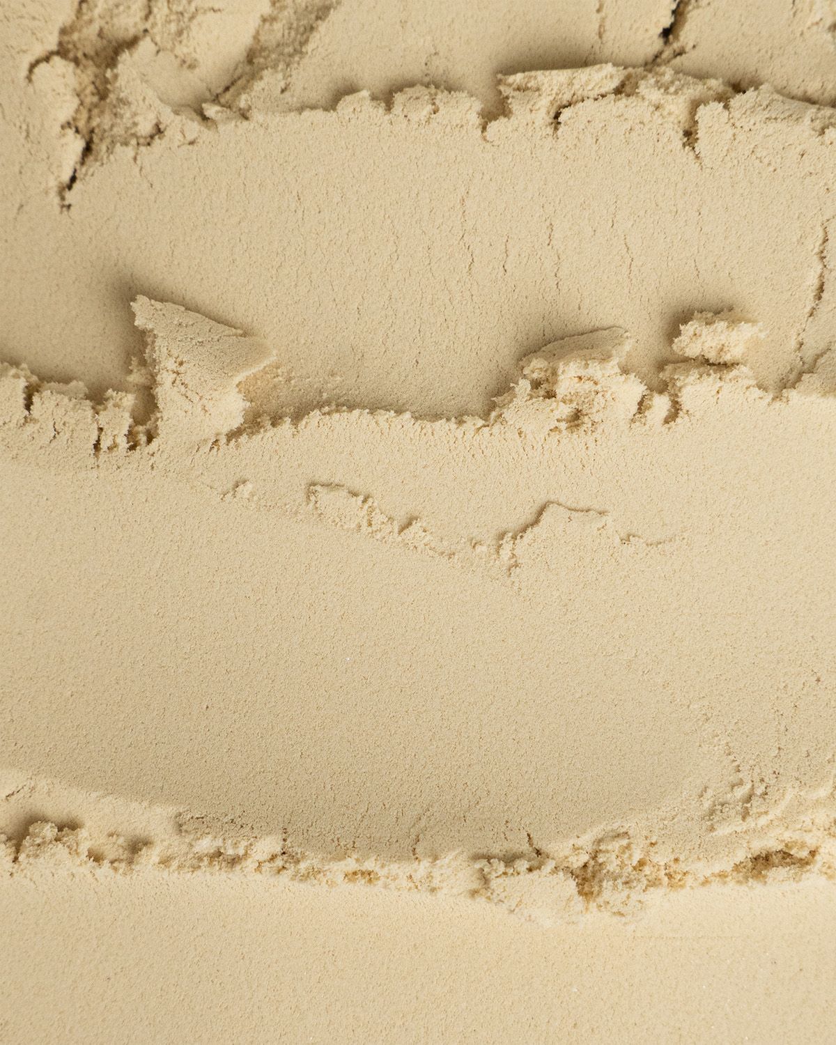 Nahaufnahme von Bio Erbsenprotein Pulver. Textur mit Schichten und Klumpen sichtbar.