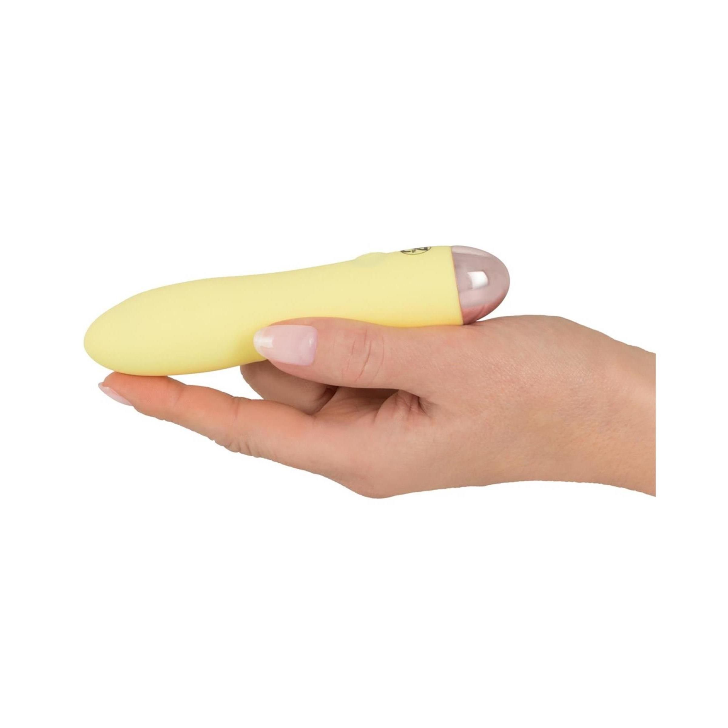 Gelber Vibrator in einer Hand gehalten. Rosa Spitze, glatte Oberfläche.