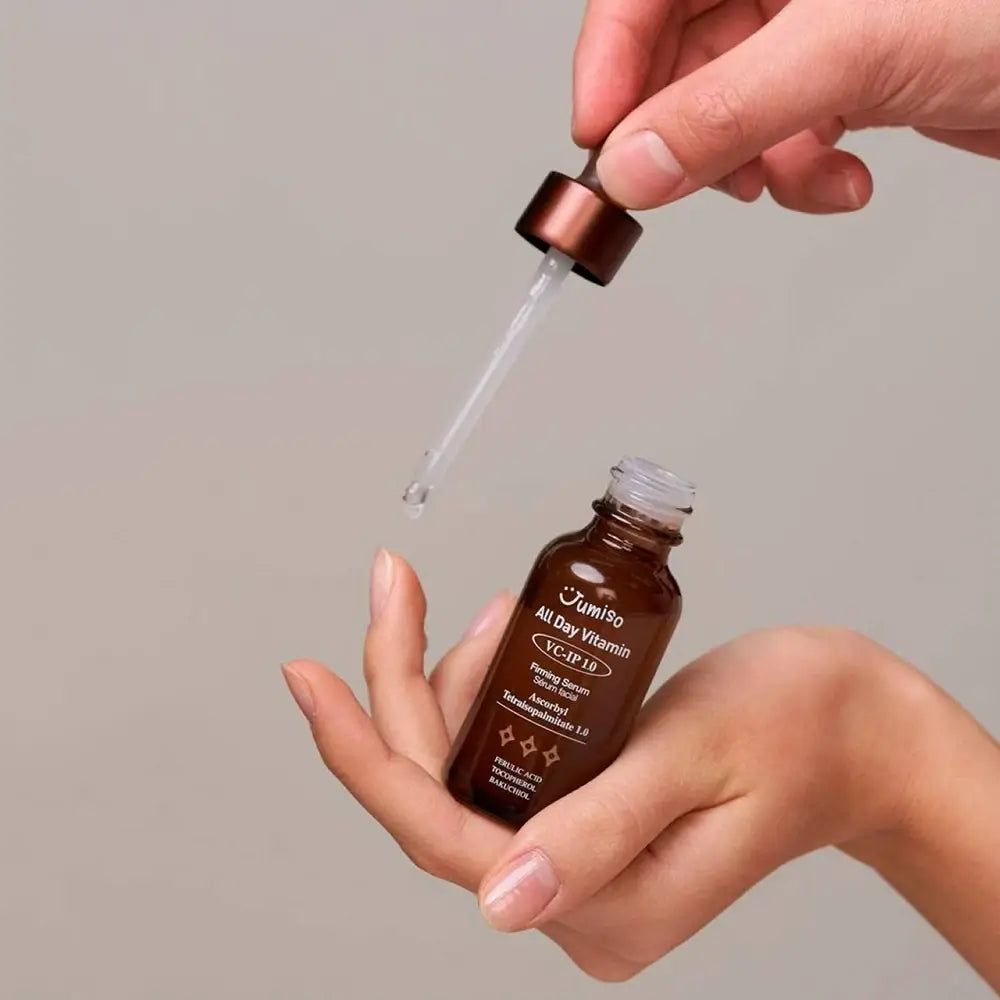 Hand hält JUMISO All Day Vitamin VC-IP 1.0 Firming Serum Flasche mit Pipette, die Serum tropft.