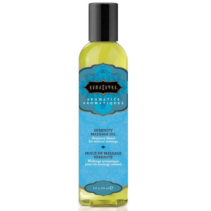 Flasche mit Massageöl. Aufschrift: Kamasutra Aromatics, Serenity Massage Oil. Blaue Etikett mit Text. Schwarzer Deckel.