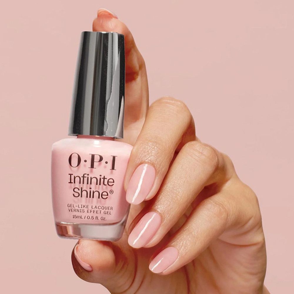 Nagellackflasche in rosa, gehalten von einer Hand mit lackierten Nägeln. OPI Infinite Shine.