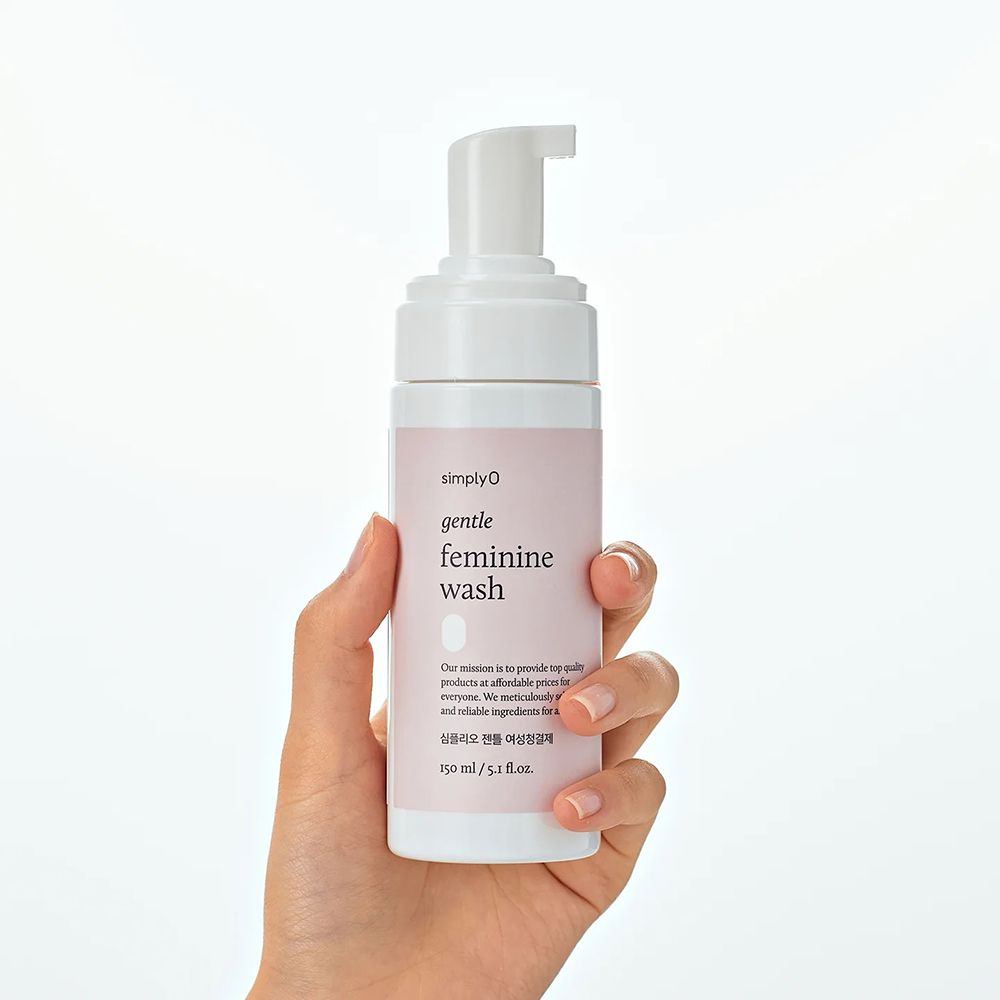 Weißer Spender, gehalten von einer Hand. Rosa Etikett mit Aufschrift: SIMPLYO gentle feminine wash. Text in koreanischer Sprache. 150 ml/5.1 fl.oz.