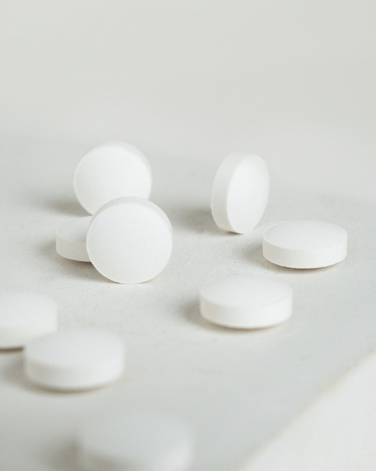 Mehrere weiße Koffein-Tabletten auf hellem Untergrund.