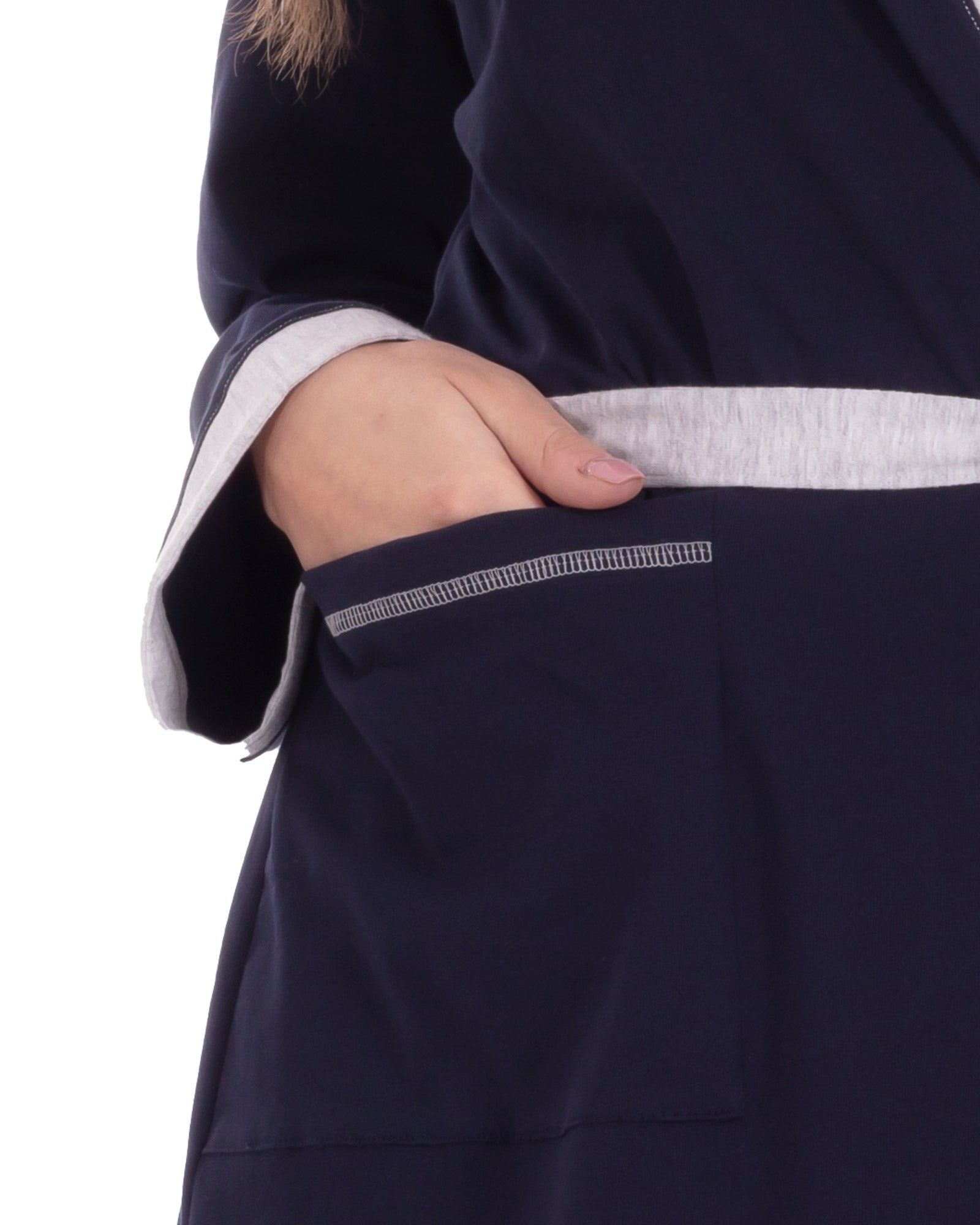 Blauer Morgenmantel aus Bio-Baumwolle mit grauen Akzenten. Eine Hand in der Tasche. Detailaufnahme.