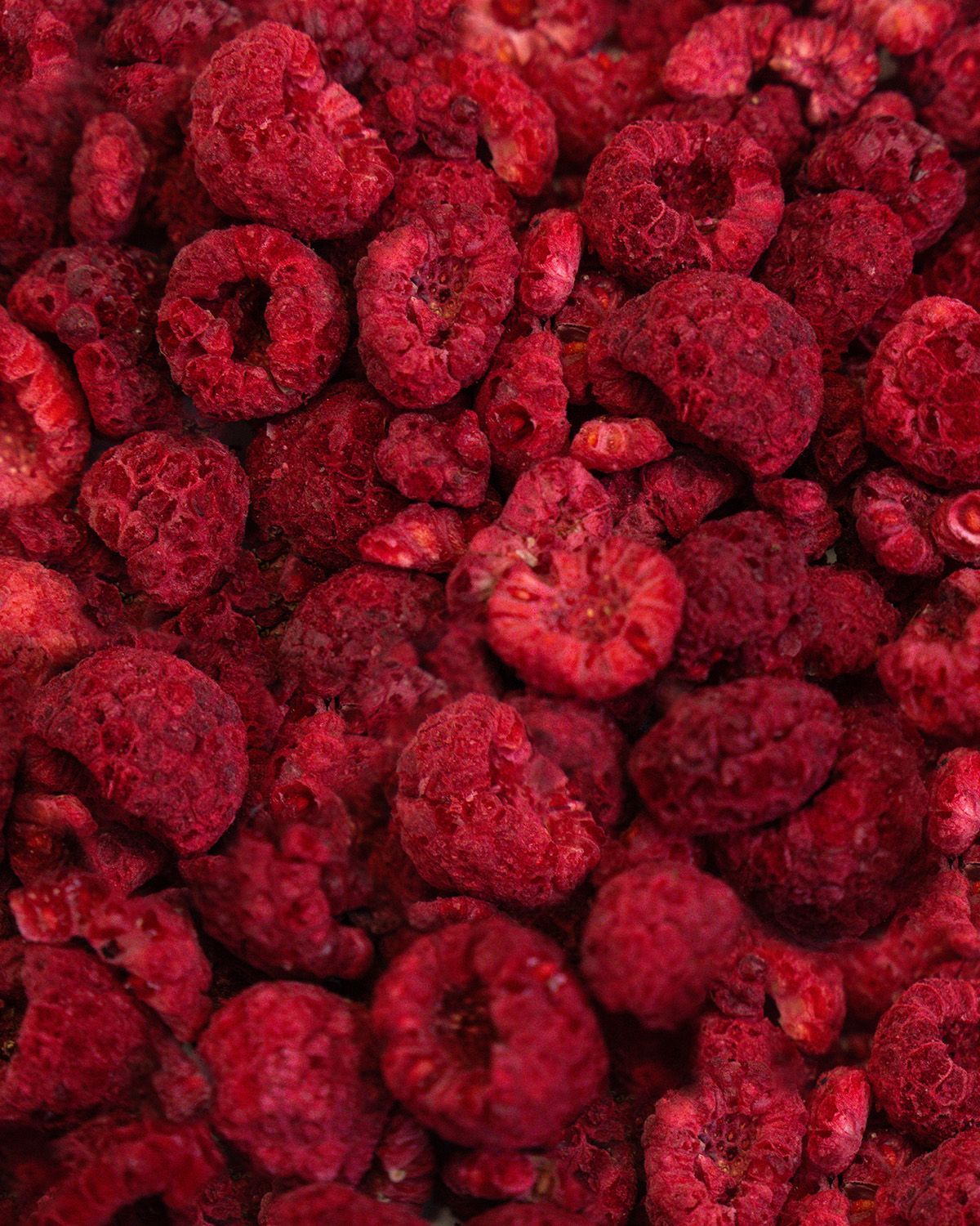 Nahaufnahme von gefriergetrockneten Himbeeren. Die Himbeeren sind rot und haben eine unregelmäßige Form.