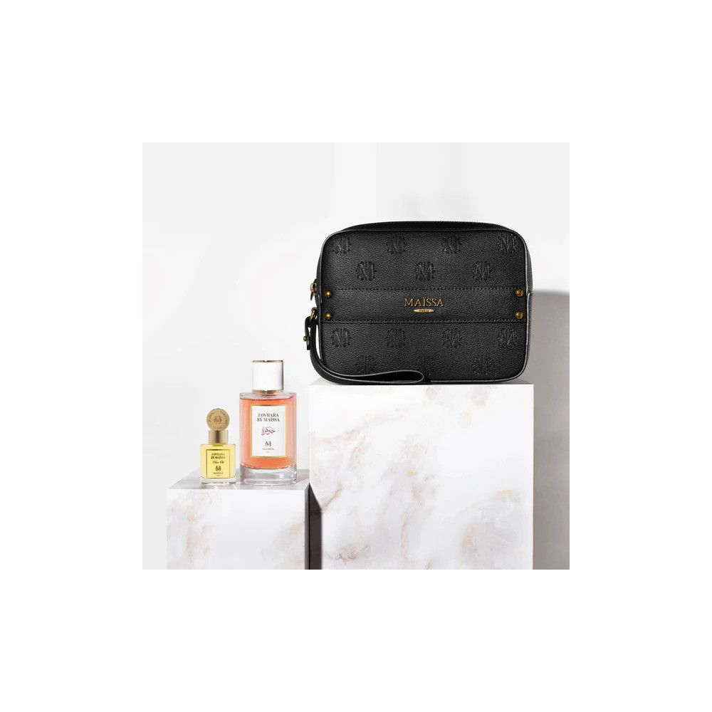 Schwarze Tasche, Parfümflasche und Flakon auf weißen Blöcken. Tasche mit MAISSA-Logo. Parfümflasche mit Etikett.