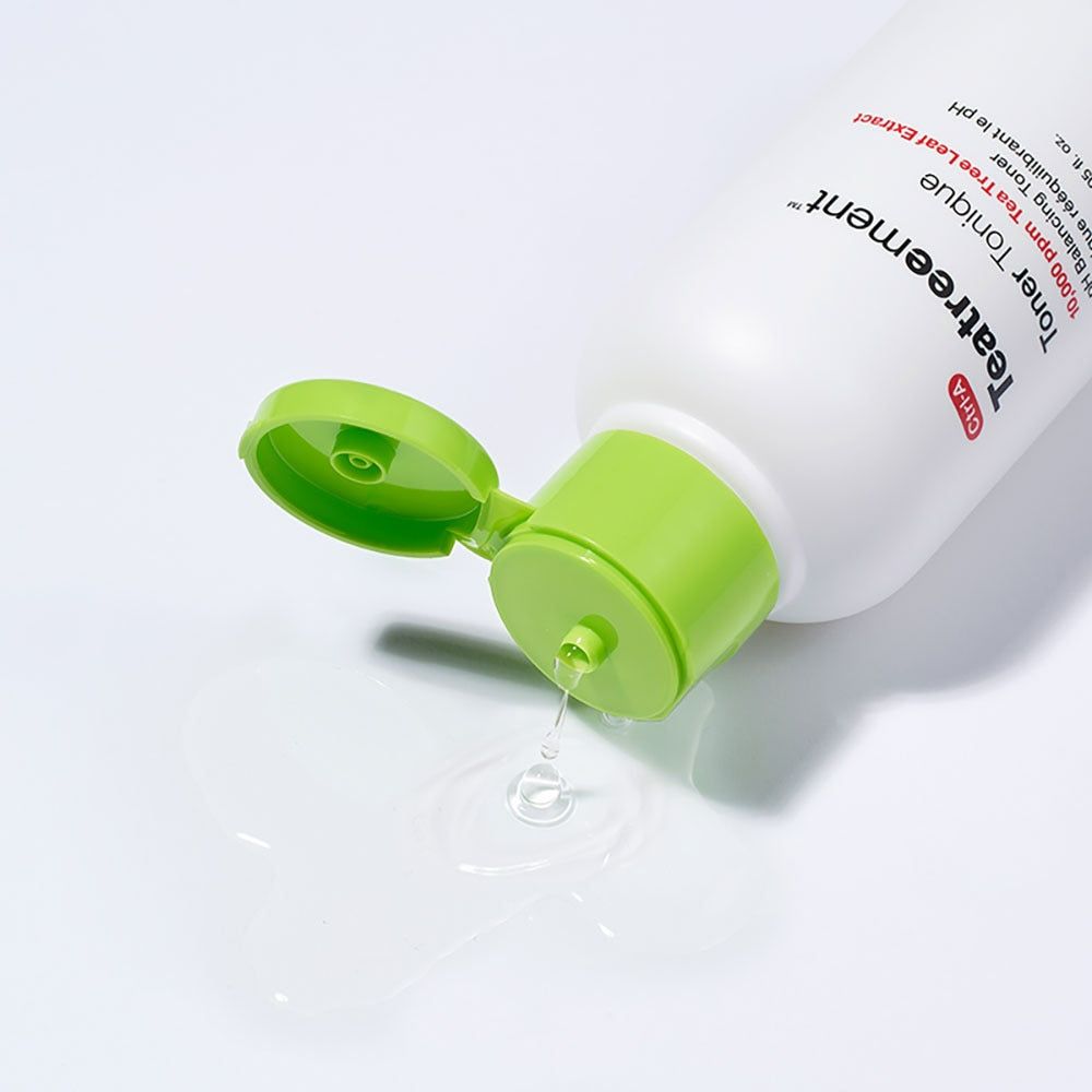 Weiße Flasche mit grünem Deckel, geöffnet. Flüssigkeit tropft heraus. Aufschrift: Teatreement Toner Tonique. Marke: Dr.Jart+.