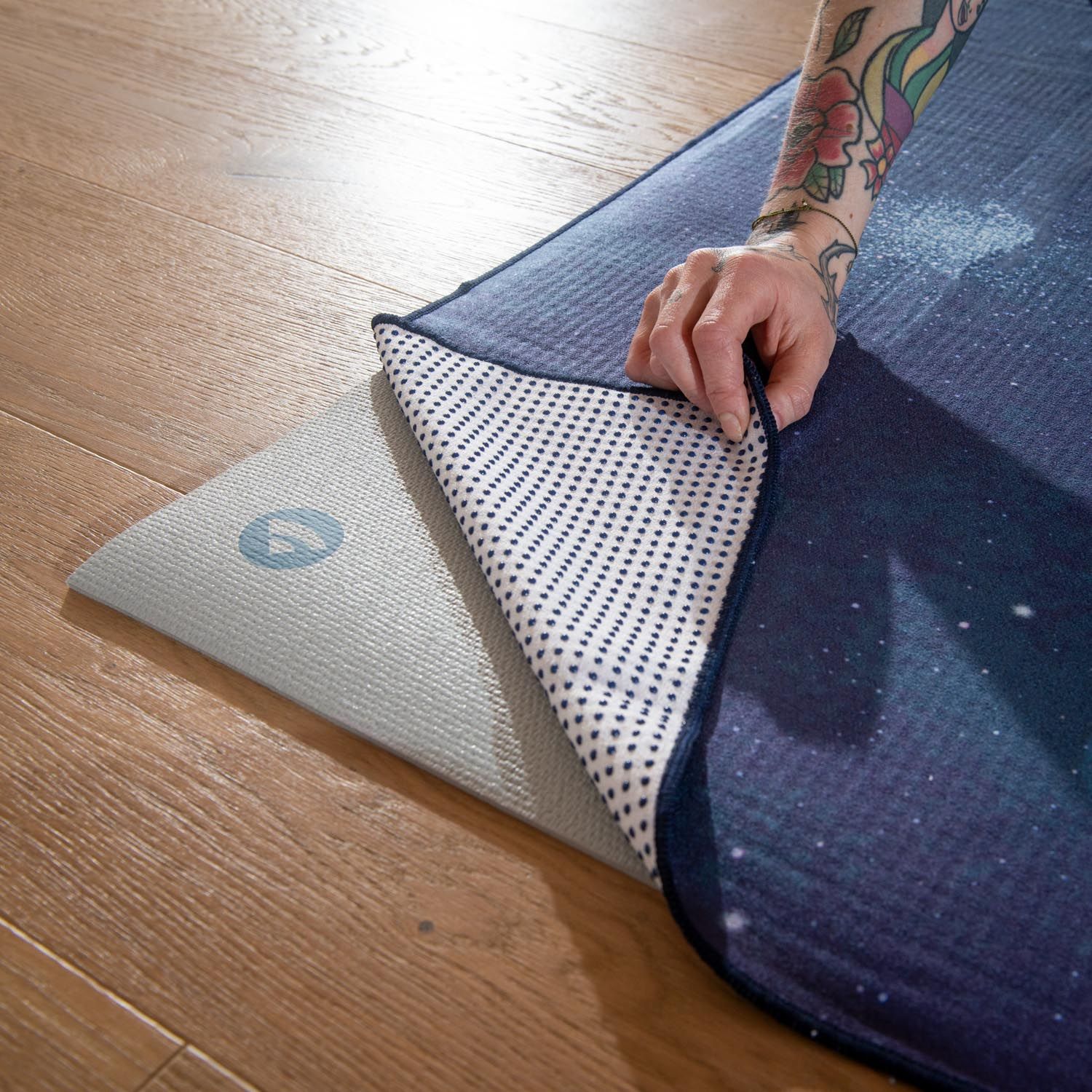 Person hält Yoga-Tuch, nightblue, mit Mond-Design. Rückseite mit weißen Punkten. Logo sichtbar.