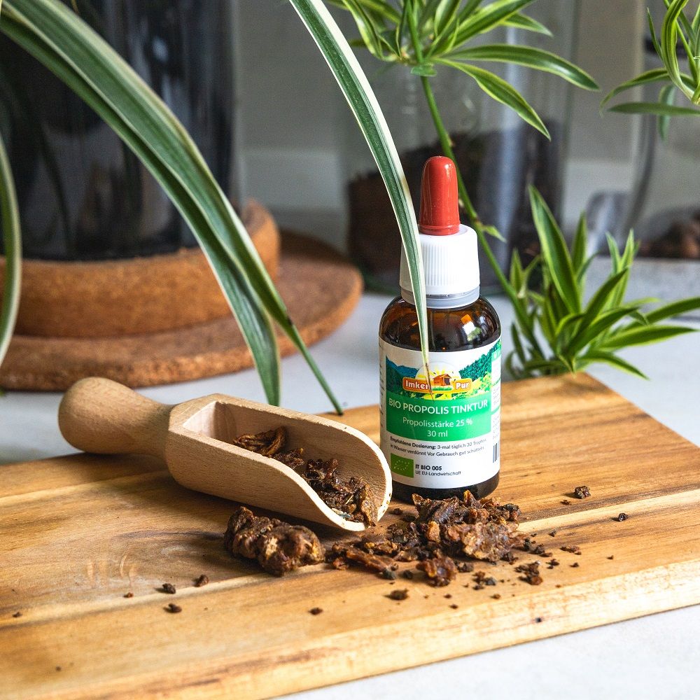 Holzbrett mit Propolis-Stücken und Holzschaufel. Flasche "ImkerPur Bio Propolis Tinktur" daneben.
