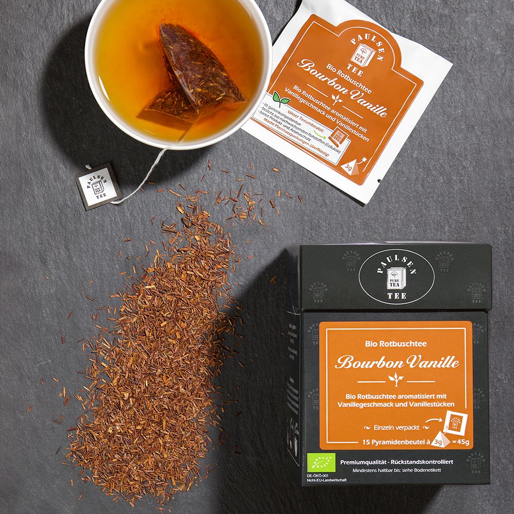 Tasse Tee, Teebeutel und lose Teeblätter. Verpackung "Bio Bourbon Vanille" daneben.