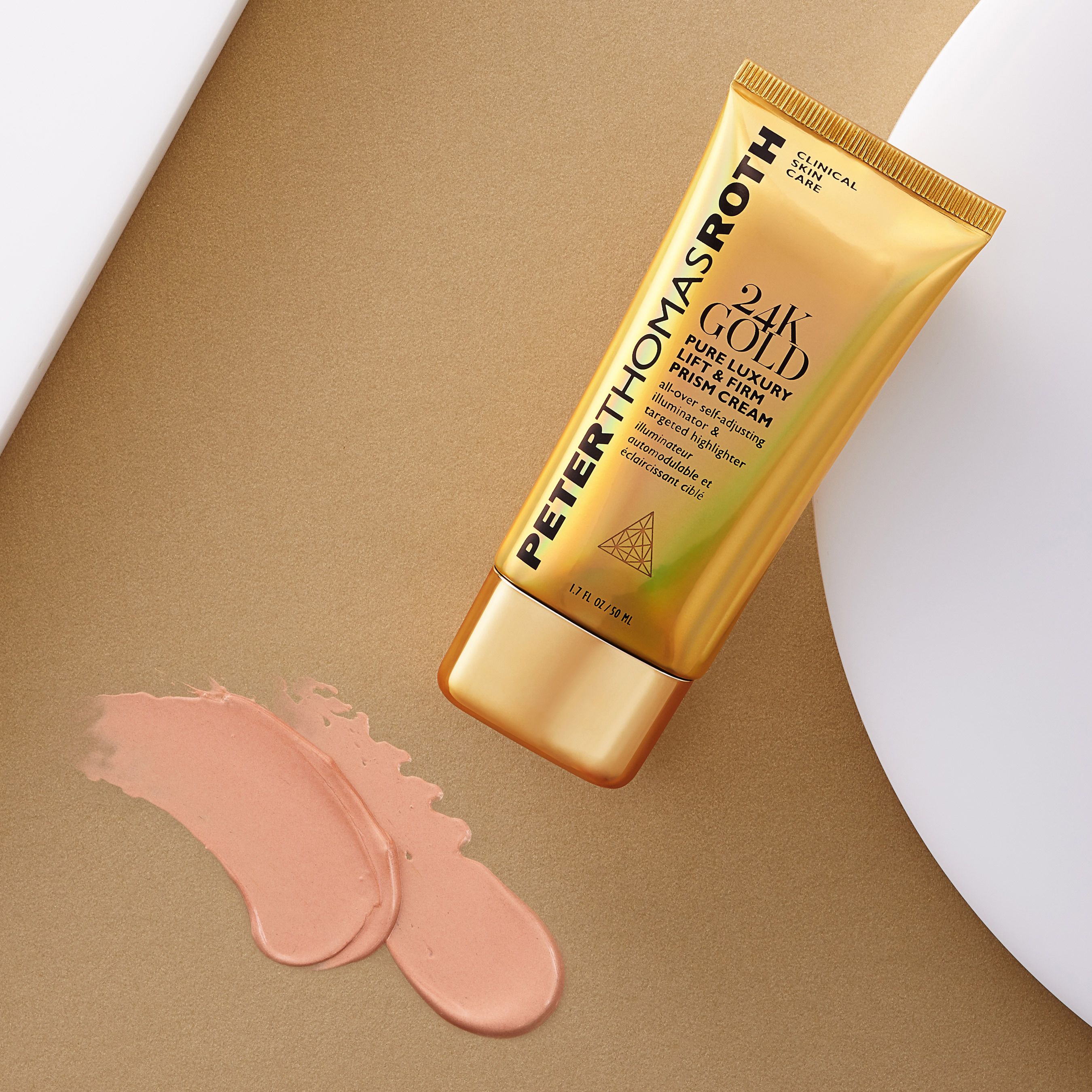 Goldfarbene Tube mit Produktname und Schriftzug. Peter Thomas Roth 24K Gold Pure Luxury Lift & Firm Prism Cream. Creme-Ausfluss daneben.