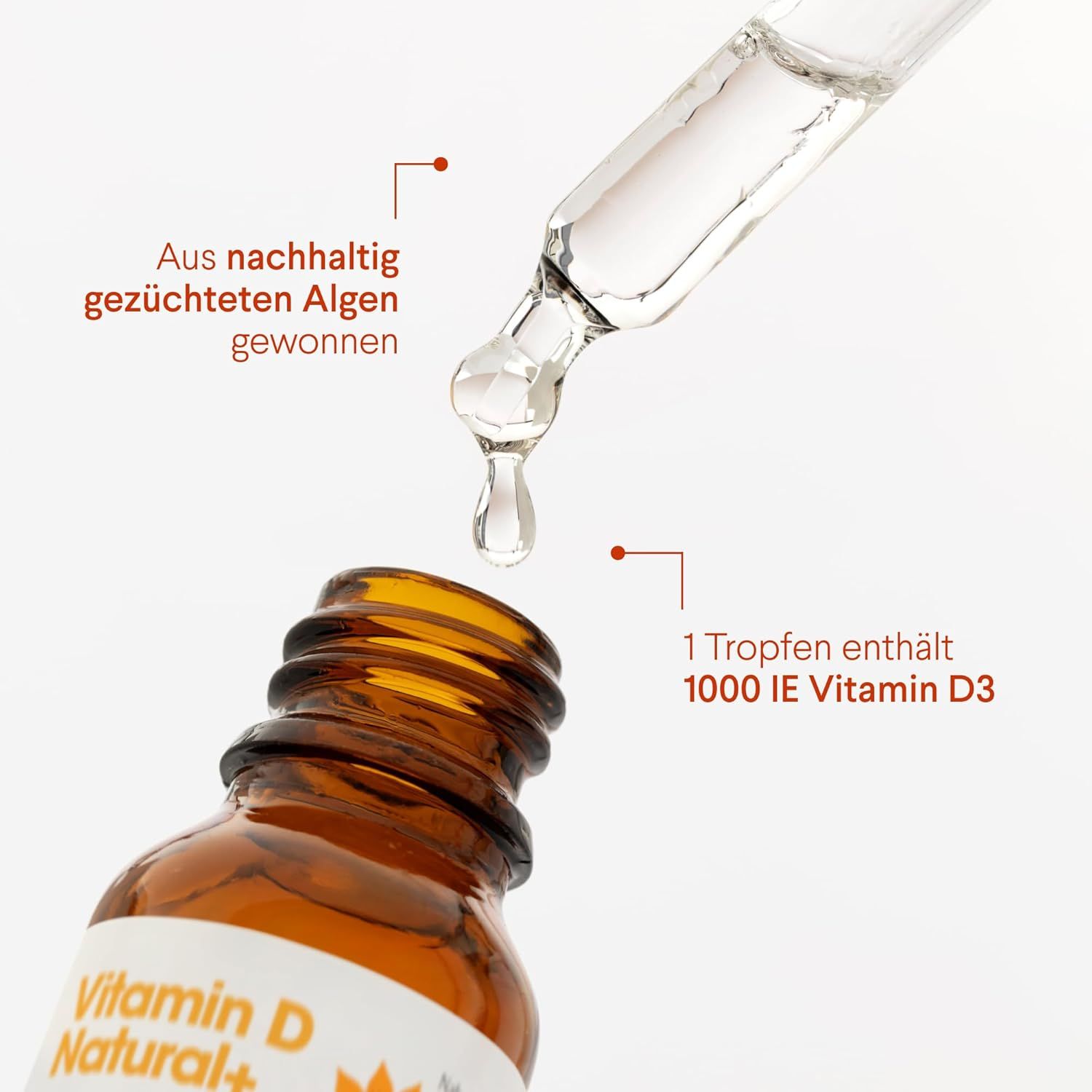 Braune Glasflasche mit Tropfer. Tropfen fallen aus dem Tropfer. Aufschrift: Vitamin D Natural+. 1 Tropfen enthält 1000 IE Vitamin D3.
