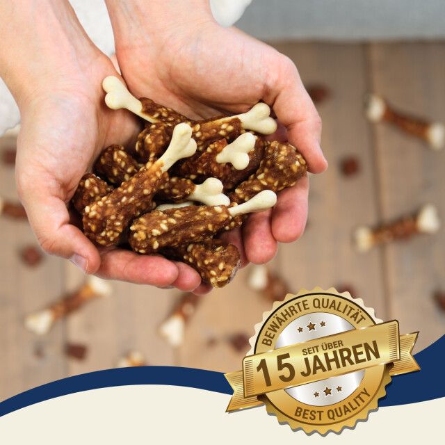 Hände halten Hühnchenschenkel-Snacks. Qualitätsauszeichnung: Bewährte Qualität, seit 15 Jahren.