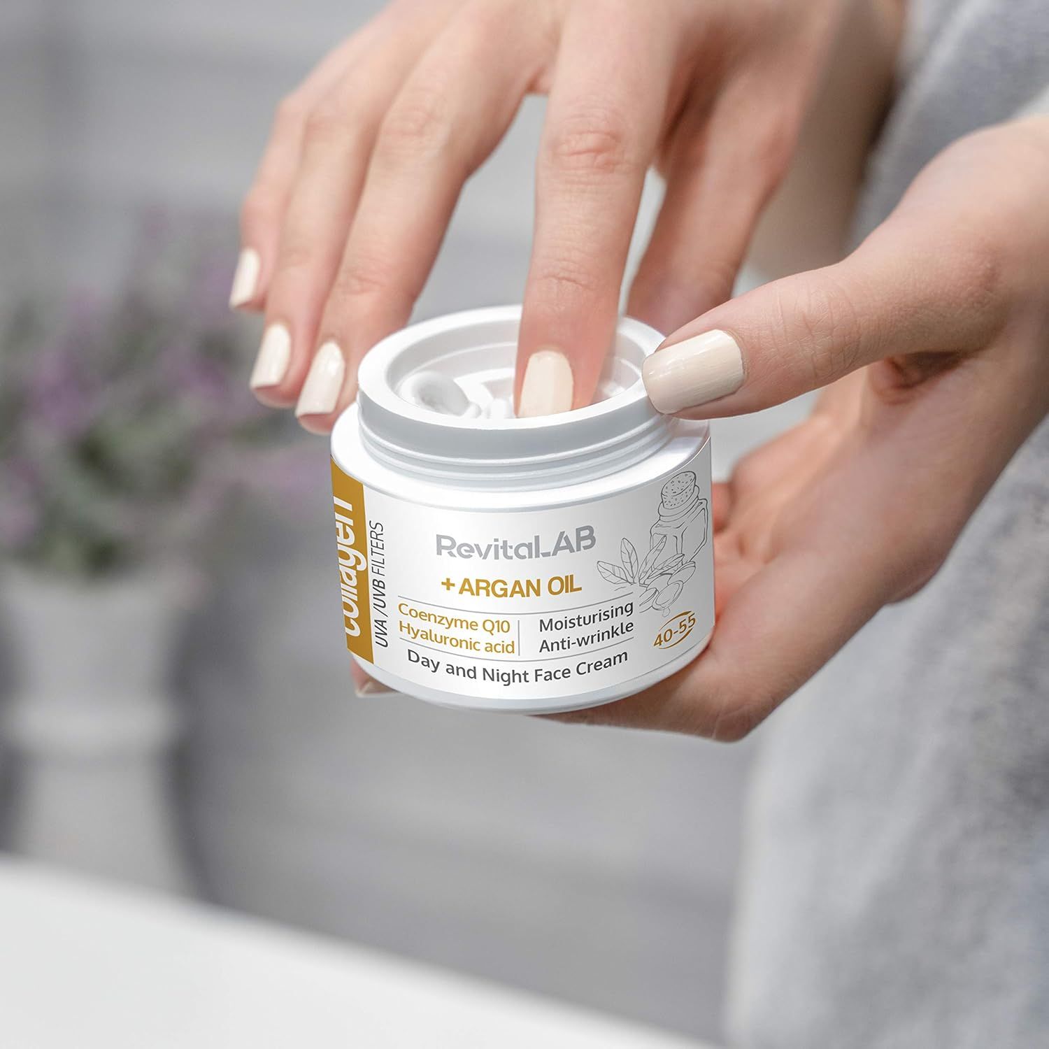 Hände halten einen Creme-Tiegel. Aufschrift: RevitaLAB + ARGAN OIL, Collagen, UVA/UVB Filters, Coenzyme Q10, Hyaluronic acid, Day and Night Face Cream.