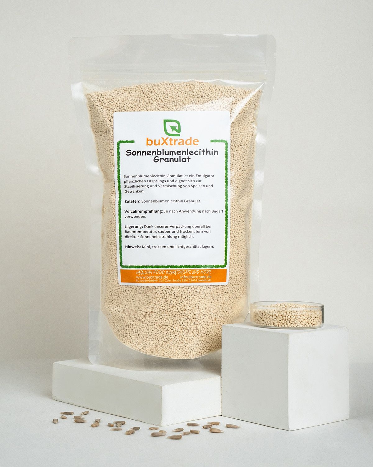 Verpackung mit buXtrade Sonnenblumenlecithin Granulat, daneben ein Glas mit Granulat.