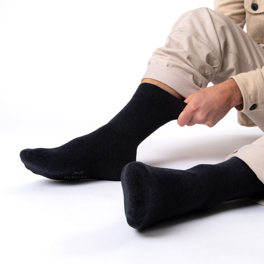 Schwarze Socken ohne Gummibund werden von einer Person angezogen. Baumwollsocken.