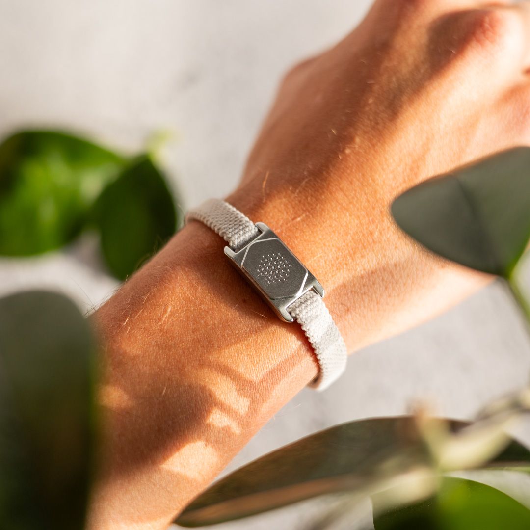 Handgelenk mit getragenem, grauem Armband. Das Armband hat ein silberfarbenes Element und ein Textilband.