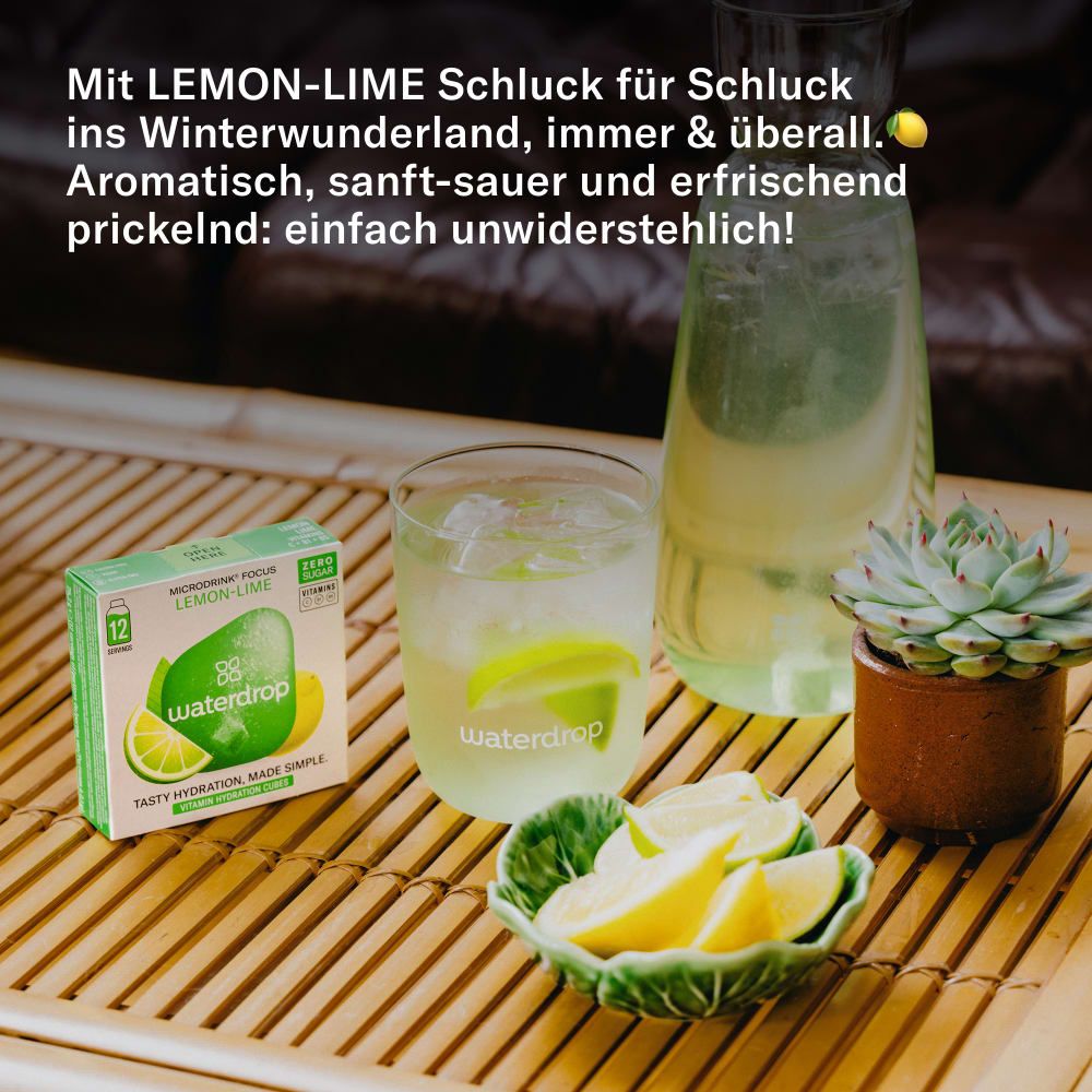 Ein Glas und eine Karaffe mit waterdrop® Microdrink Lemon Lime, garniert mit Limettenscheiben.