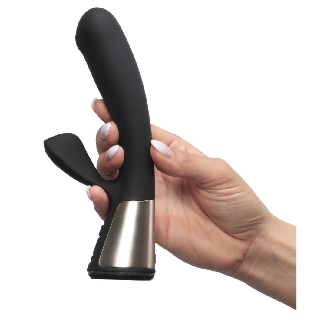 Schwarzer Vibrator, gehalten von einer Hand. Silberfarbener Sockel. Gebogene Form mit einem gebogenen Teil und einem kleineren Teil.