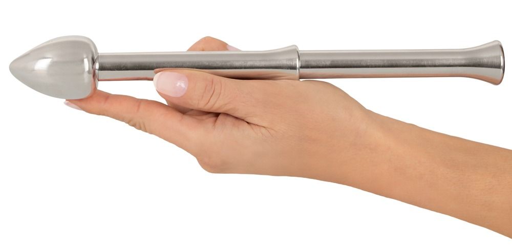 Hand hält einen glänzenden Metall-Stimulator mit spitz zulaufendem Kopf.