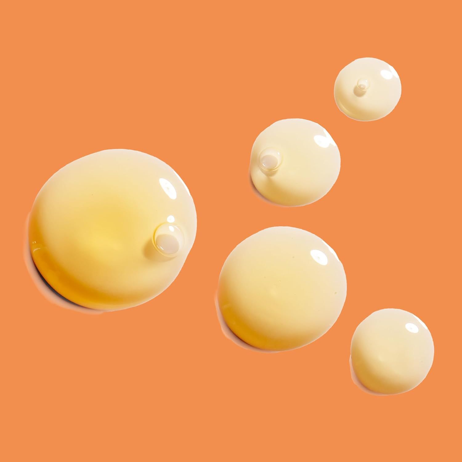 Tropfen von goldenem Serum auf orangefarbenem Hintergrund.