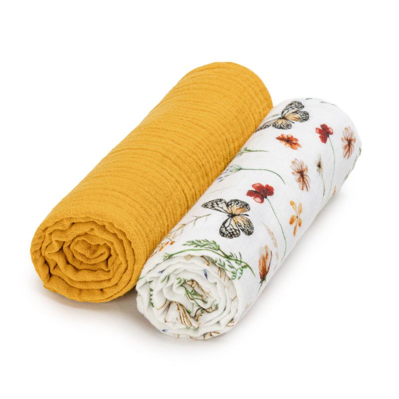 Zwei gerollte Musselin-Windeln. Eine senffarbene, eine mit Blumen- und Schmetterlingsmuster. Beide auf weißem Hintergrund.