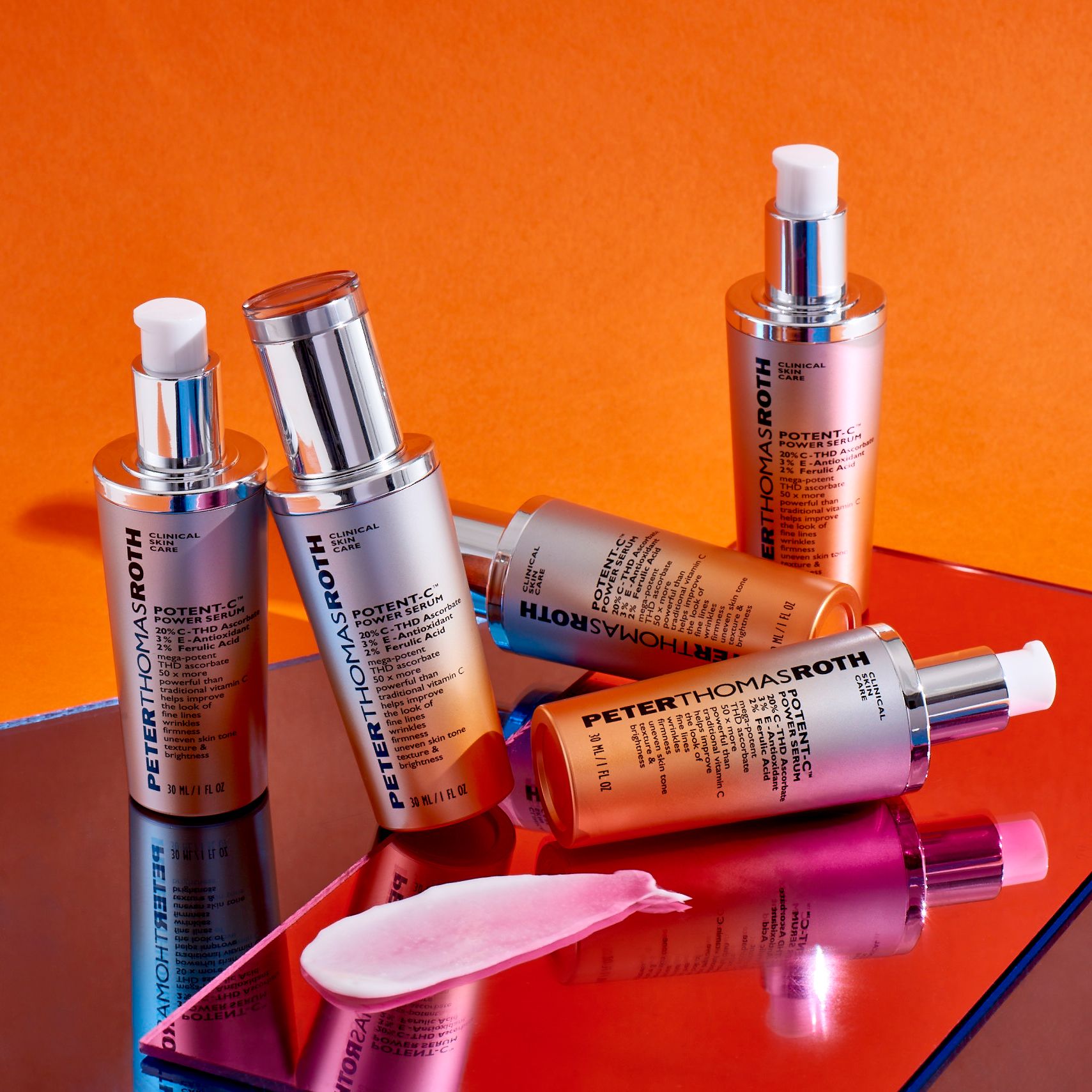 Mehrere Serumflaschen. Aufschrift: Potent-C Power Serum. Silberne Kappen und orangefarbener Farbverlauf. Auf orangefarbenem Hintergrund.