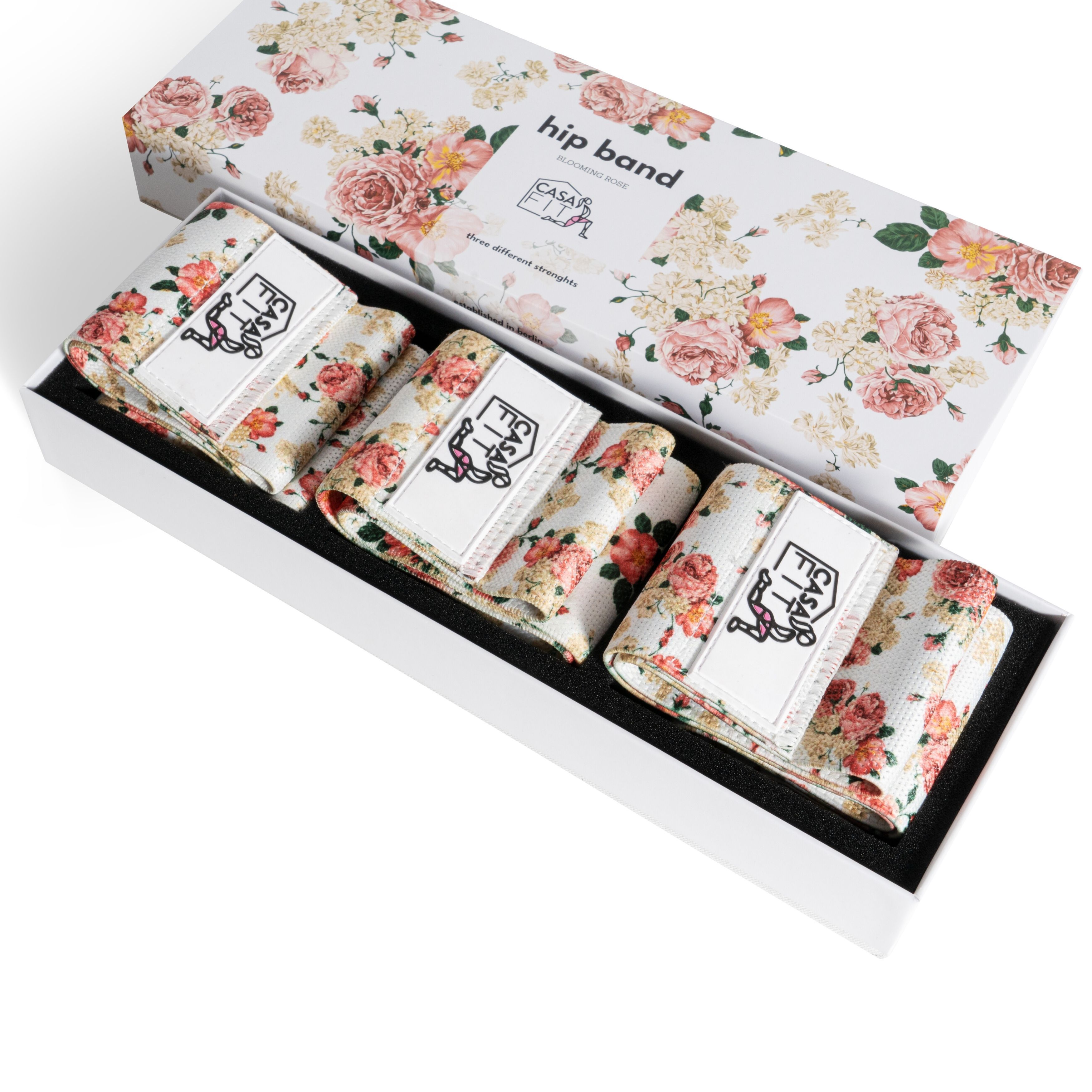 Set Hüftbänder in floraler Box. Drei Bänder mit Logo, floralem Muster. Box mit floralem Muster und Schriftzug.