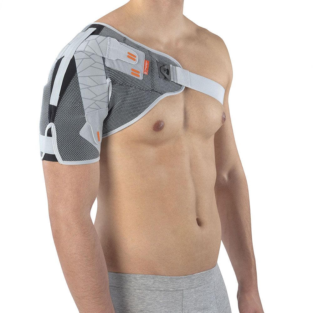 Schulterkompressionsbandage. Grau-weißes Material, Schulter- und Armabdeckung. Klettverschlüsse und Gurte. Auf Person getragen.