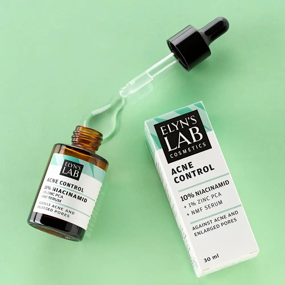 Braune Glasflasche mit Pipette und Tropfen Serum. Daneben eine weiße Schachtel mit grünem Akzent und Text: Acne Control, 10% Niacinamid.