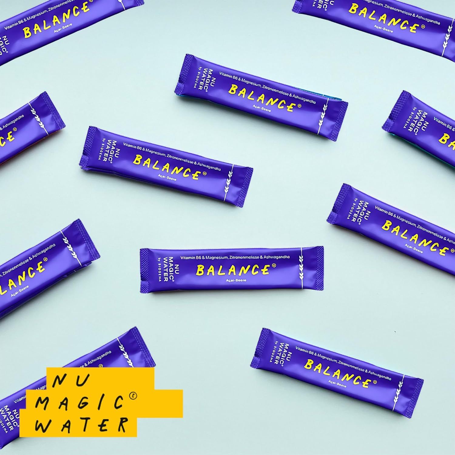 Mehrere lila Sticks mit "BALANCE" und "NU MAGIC WATER" von BIOGENA auf hellblauem Hintergrund. Produkt im Fokus.