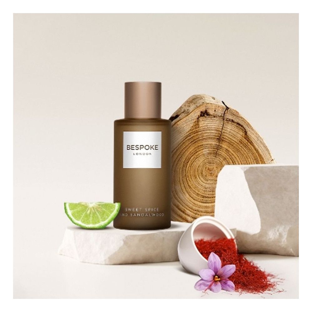 Parfümflasche mit Aufschrift Bespoke London, Sweet Spice and Sandalwood. Mit Holz, Limette und Gewürzen dekoriert.