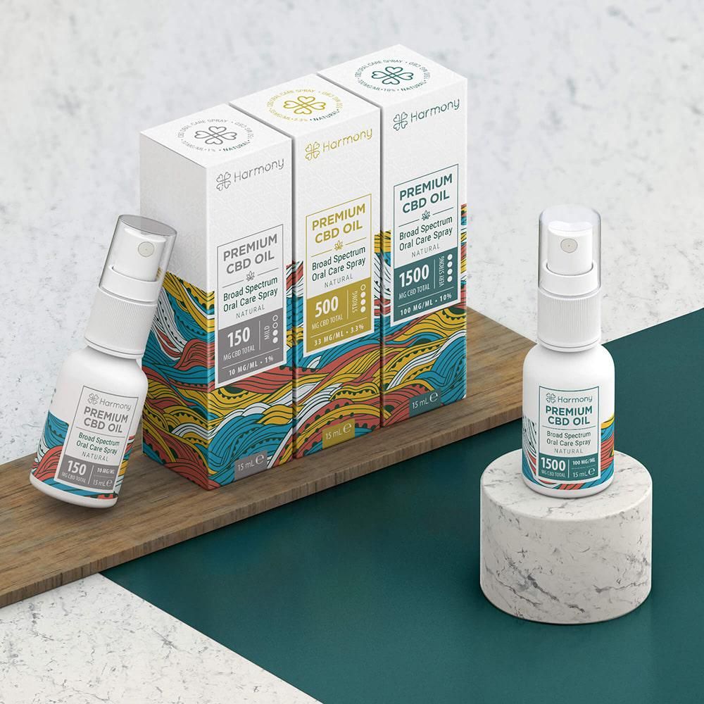 Drei Schachteln und zwei Sprühflaschen mit Harmony-Logo und "Premium CBD Oil". Flaschen auf Holz und Sockel.