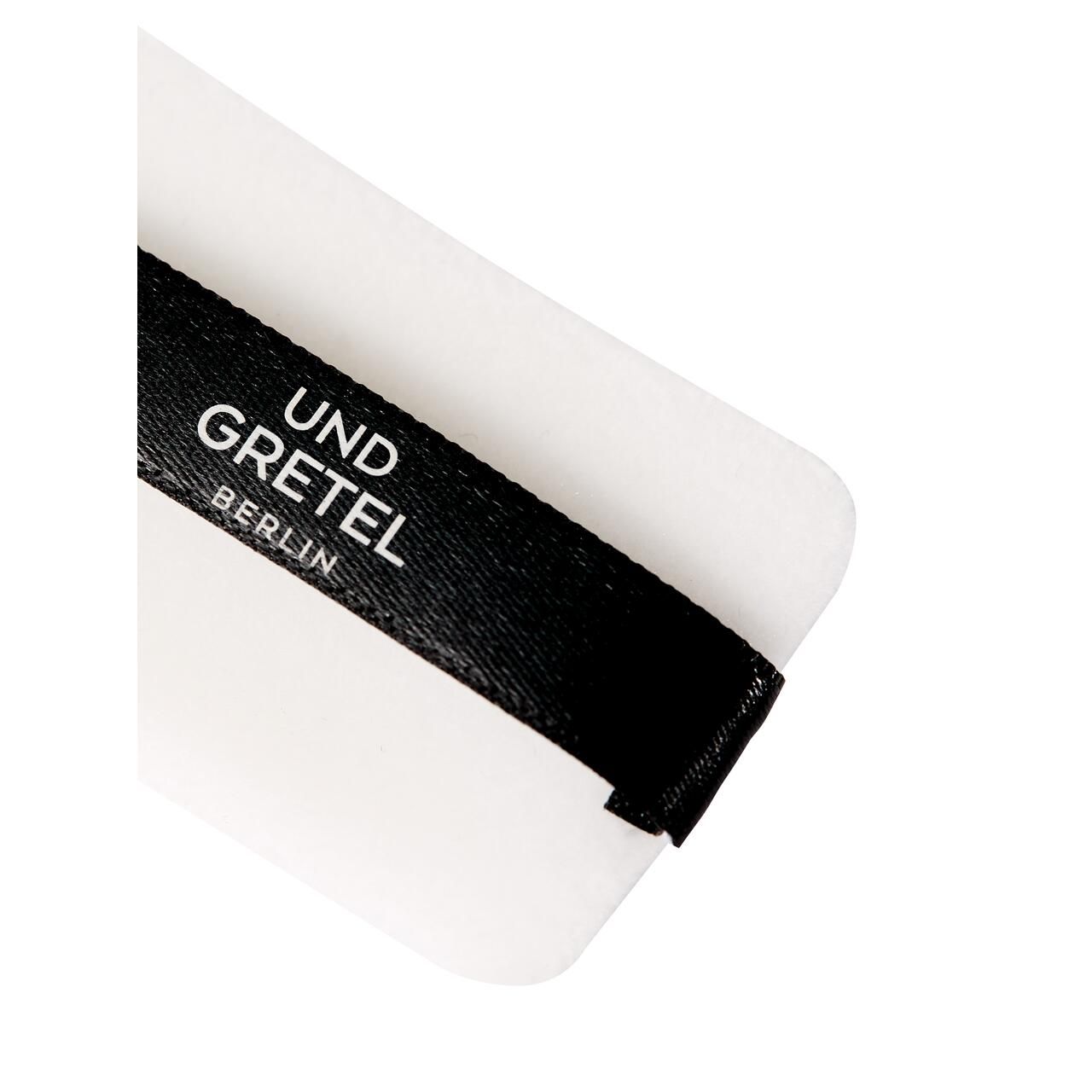 Weißes Puder-Pad mit schwarzem Band. Auf dem Band steht 'UND GRETEL BERLIN'.