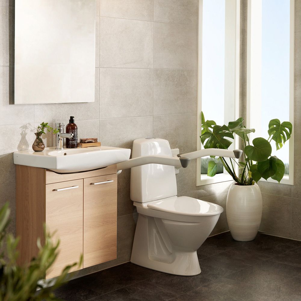 Badezimmer mit Toilette, Waschbecken und einem weißen Stützklappgriff.