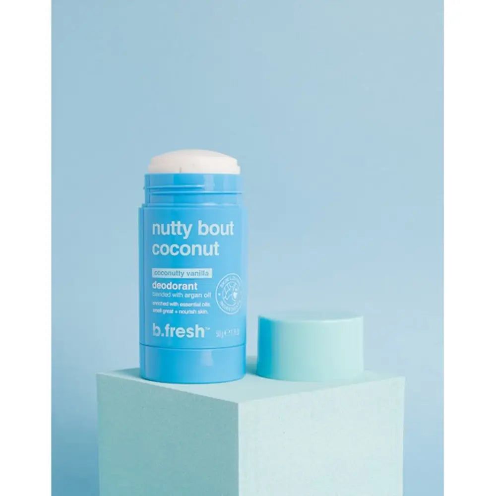 Blaues Deodorant mit weißem Deckel. Aufschrift: "nutty bout coconut". Daneben der Deckel. Auf einem blauen Podest.