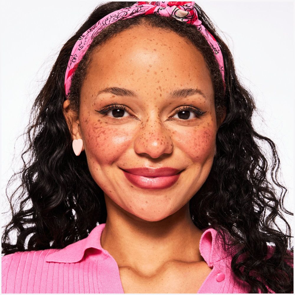 Porträt einer Frau mit Lippenstift. Sie trägt ein Stirnband und Ohrringe.